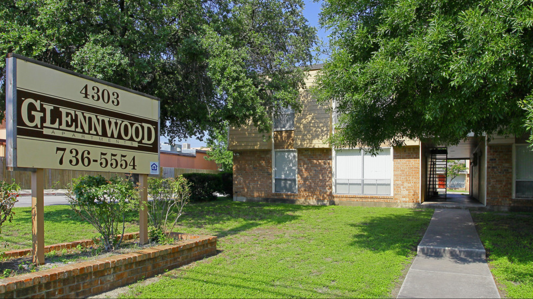 Exterior view of Glennwood apartments with signage and buildings.