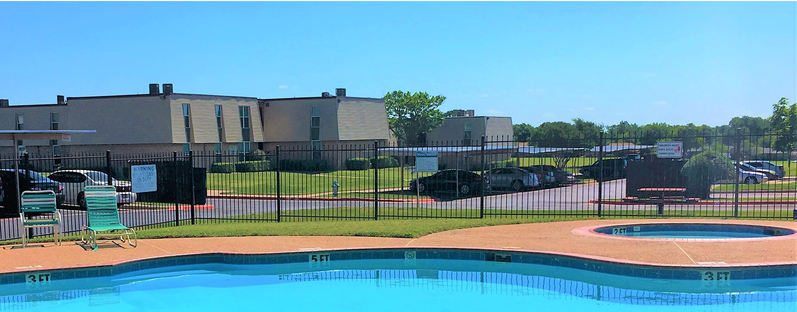 A view of the pool at Hampton Terrace with the buildings and parking lot in the back.