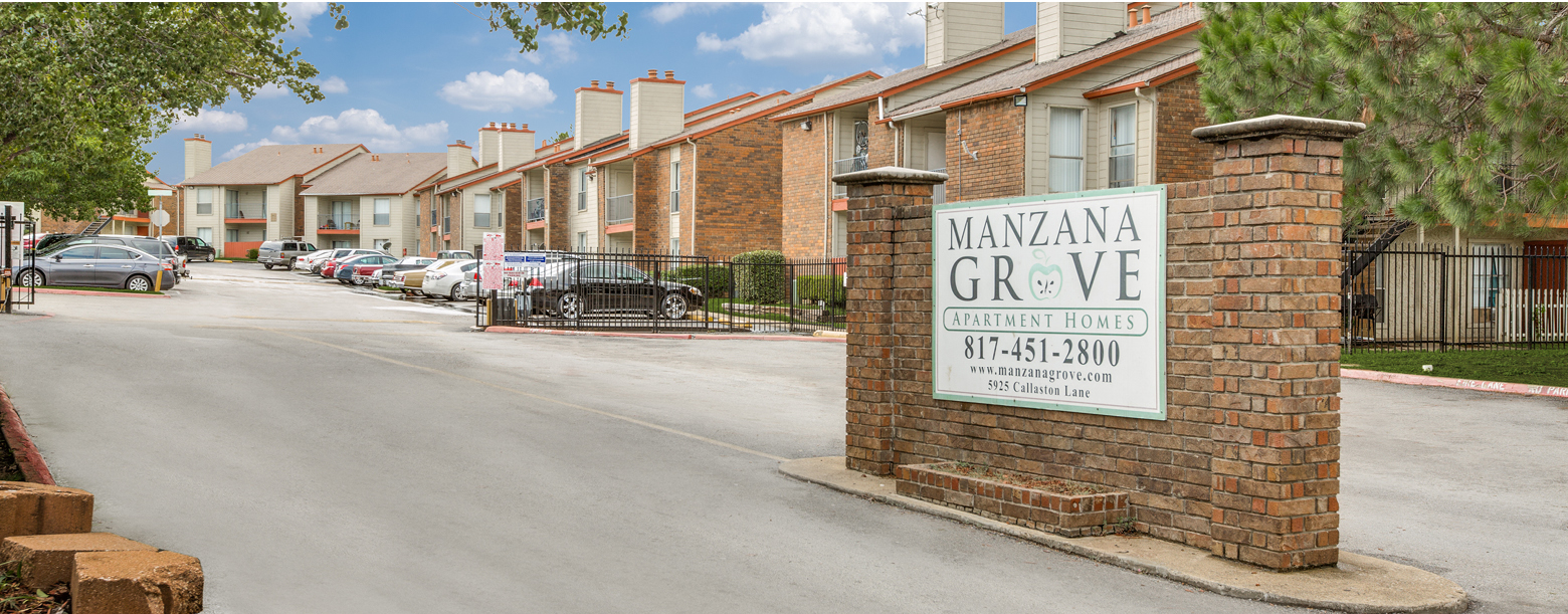 The entrance to Manzana Grove has an open gate leading into the complex, and the signage lies to the right.