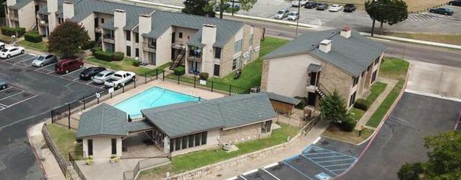 Aerial view of Parkview shows the parking lot, pool area, apartment entrance, and several of its buildings.