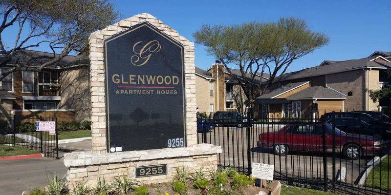 A close view of the signage at Glenwood Apartment Homes with the entrance to the complex in the back.