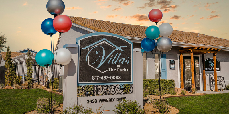 Signage at Villas at the Parks with the leasing center in the background.